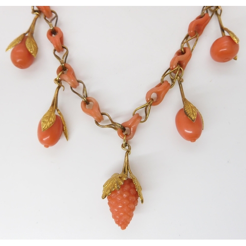 824 - A CARVED CORAL FRUIT NECKLACEthe fruit mounted with engraved and chased yellow metal leaves, with co... 