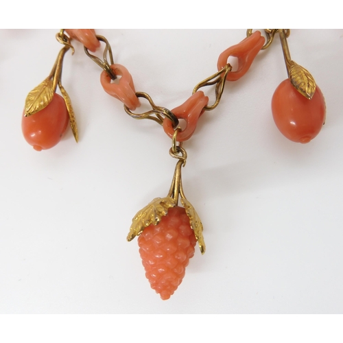 824 - A CARVED CORAL FRUIT NECKLACEthe fruit mounted with engraved and chased yellow metal leaves, with co... 