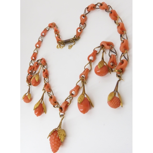 824 - A CARVED CORAL FRUIT NECKLACEthe fruit mounted with engraved and chased yellow metal leaves, with co... 