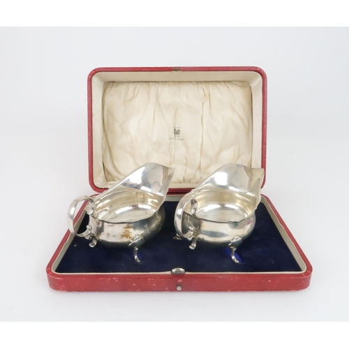 905 - A CASED PAIR OF SILVER SAUCEBOATS by Martin Hall & Co. Sheffield 1919, of classic form with scro... 