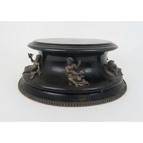 933 - AN EBONISED WOODEN STANDof circular form the concave side applied with seven silver cherubs by Thoma... 