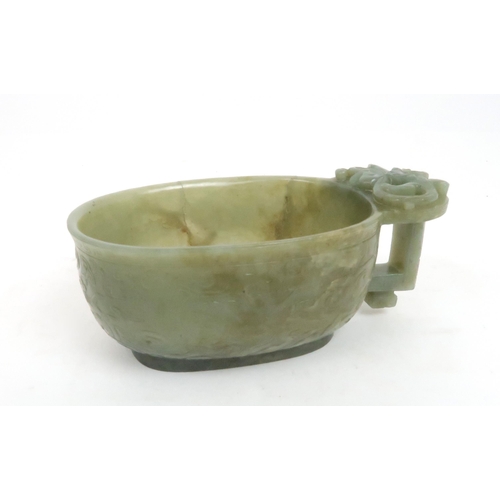 201 - A CHINESE JADE ARCHAIC STYLE VESSEL carved with dragons amongst cloud scrolls, the protruding handle... 