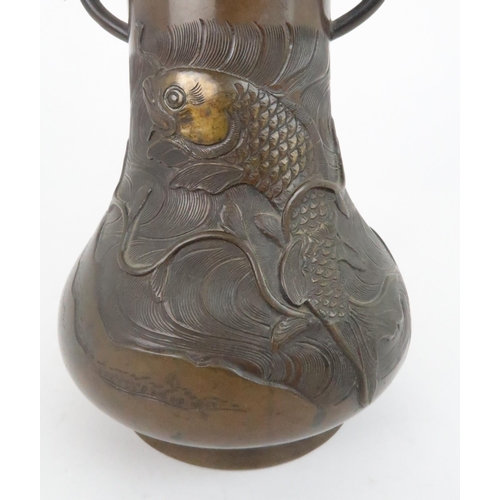 211 - A JAPANESE BRONZE TWO HANDLED VASEcast with a rising carp on raging sea, with leaf capped handles,19... 