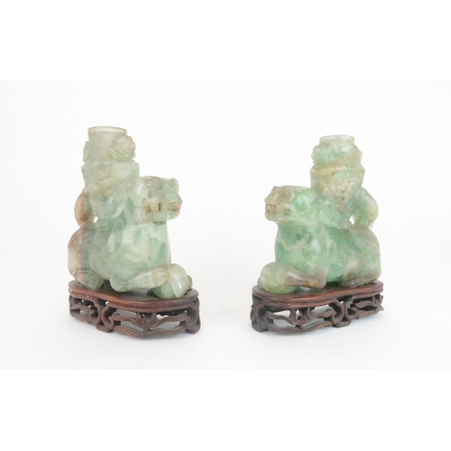 216 - A PAIR OF CHINESE FLUORITE CARVED SHISHIeach seated and resting on a ball, with foliate carved vases... 