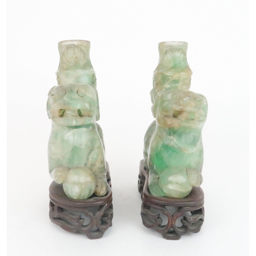 216 - A PAIR OF CHINESE FLUORITE CARVED SHISHIeach seated and resting on a ball, with foliate carved vases... 