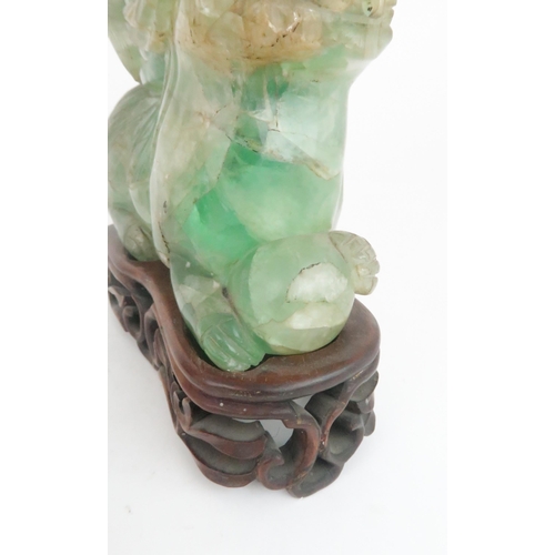 216 - A PAIR OF CHINESE FLUORITE CARVED SHISHIeach seated and resting on a ball, with foliate carved vases... 