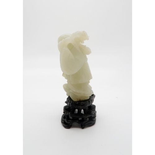 235 - A CHINESE JADE CARVING OF A FIGURE standing on the three legged toad and holding a pomegranate branc... 