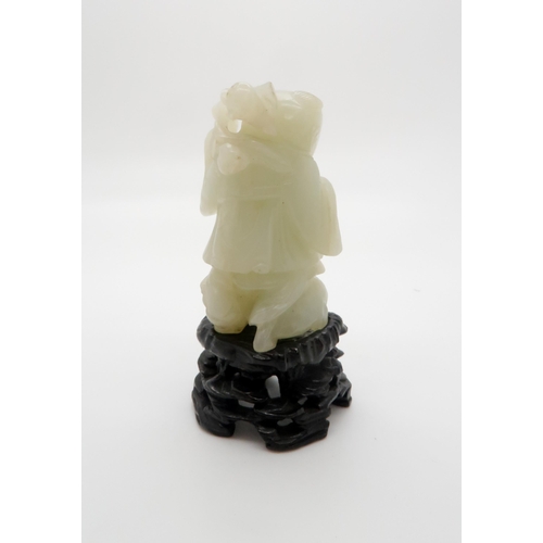 235 - A CHINESE JADE CARVING OF A FIGURE standing on the three legged toad and holding a pomegranate branc... 