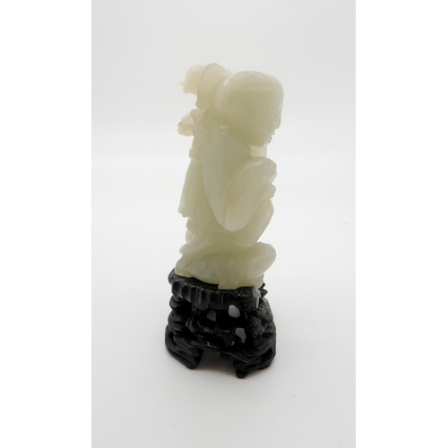 235 - A CHINESE JADE CARVING OF A FIGURE standing on the three legged toad and holding a pomegranate branc... 