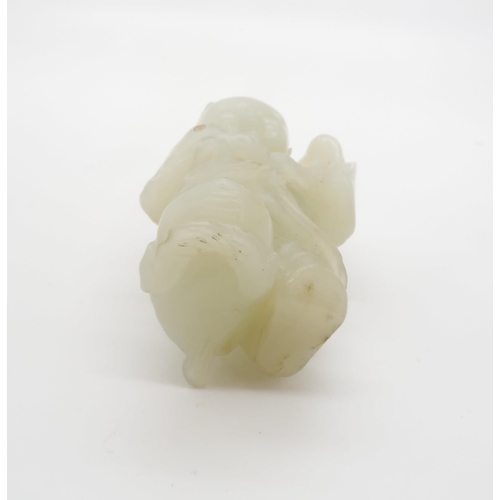 235 - A CHINESE JADE CARVING OF A FIGURE standing on the three legged toad and holding a pomegranate branc... 