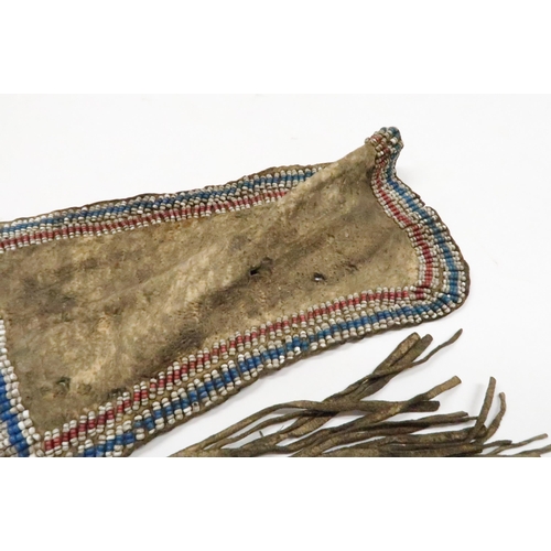 258 - AN AMERICAN PLAINS INDIAN APRONThe animal skin woven with rows of beadwork in red, white and blue, 8... 