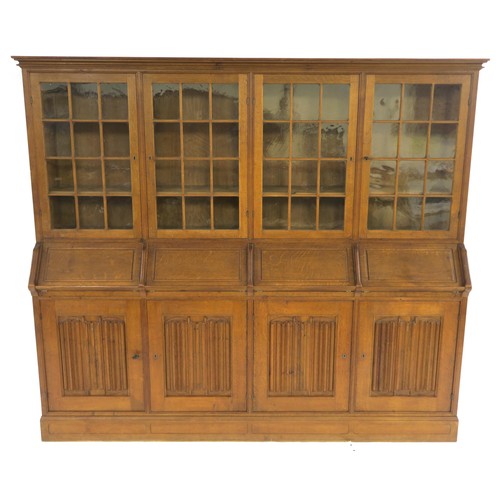 27 - AN ARTS AND CRAFTS OAK BOOKCASE with four astragal glazed doors above four fall front writing slopes... 