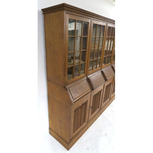 27 - AN ARTS AND CRAFTS OAK BOOKCASE with four astragal glazed doors above four fall front writing slopes... 