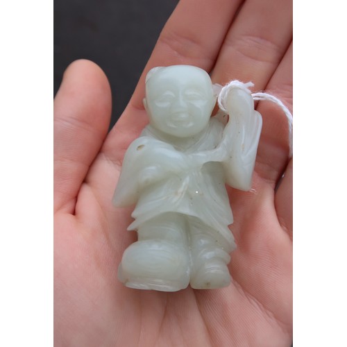 235 - A CHINESE JADE CARVING OF A FIGURE standing on the three legged toad and holding a pomegranate branc... 