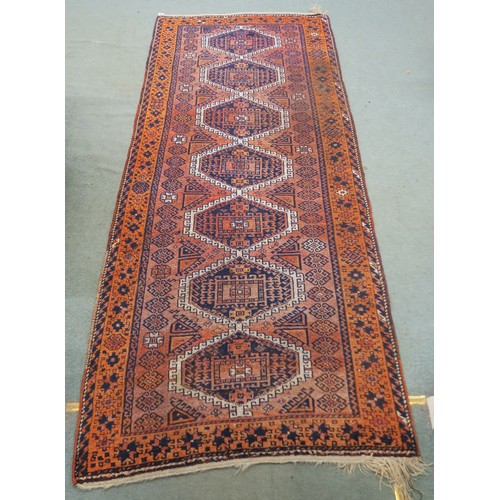 121A - A TERRACOTTA GROUND BELOUCH RUG, with seven geometric medallions and orange border, 310cm long x 138... 