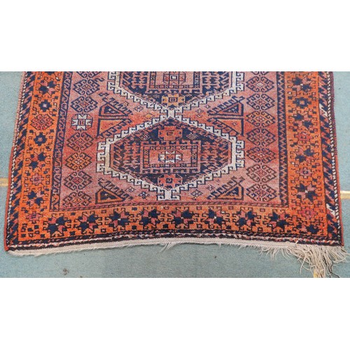 121A - A TERRACOTTA GROUND BELOUCH RUG, with seven geometric medallions and orange border, 310cm long x 138... 