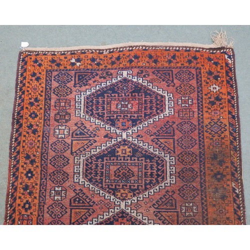 121A - A TERRACOTTA GROUND BELOUCH RUG, with seven geometric medallions and orange border, 310cm long x 138... 