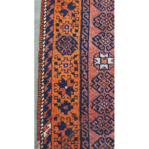 121A - A TERRACOTTA GROUND BELOUCH RUG, with seven geometric medallions and orange border, 310cm long x 138... 