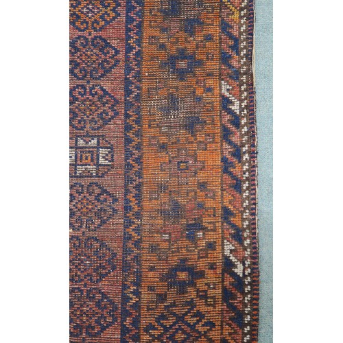 121A - A TERRACOTTA GROUND BELOUCH RUG, with seven geometric medallions and orange border, 310cm long x 138... 