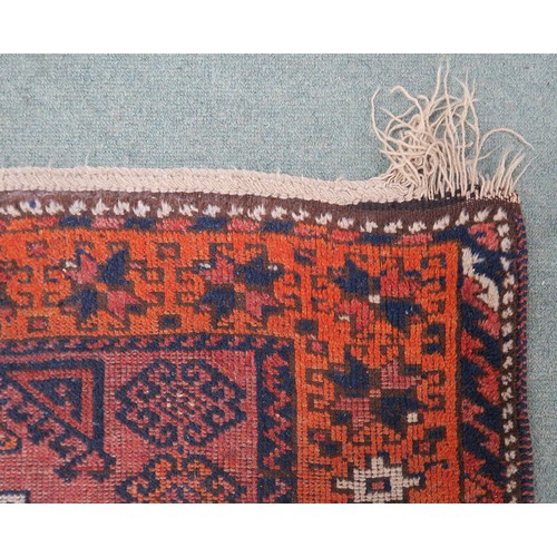 121A - A TERRACOTTA GROUND BELOUCH RUG, with seven geometric medallions and orange border, 310cm long x 138... 