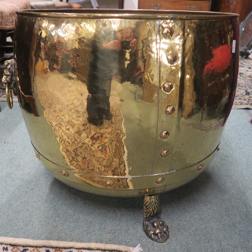 27 - A rivetted brass log bin, on lion's paw feet and with mask handles