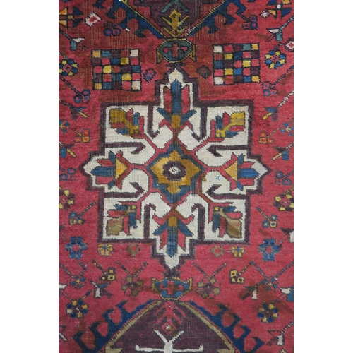 92 - A red ground Heriz runner with geometric medallions and multicoloured border, 381cm long x 88cm wide