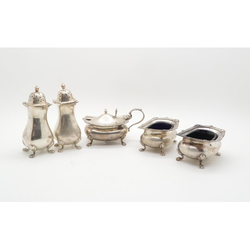 402 - A five piece silver cruet set, comprising two salts, two casters, and a mustard pot, with blue glass... 