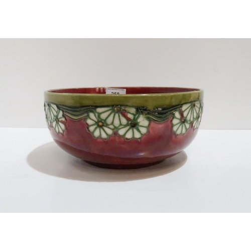 258 - A Minton Secessionist bowl with tube lined flower decoration on red ground, 22.5cm diameter