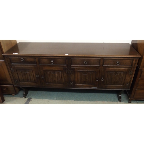 110 - A 20th century teak linen fold front sideboard with four drawers above four cabinet doors, 87cm high... 