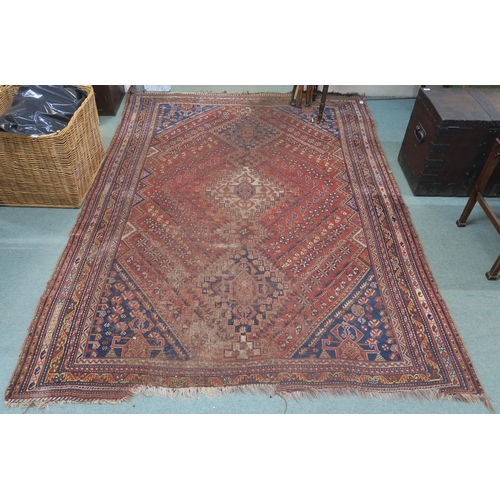 146 - A red ground Persian tribal rug with three geometric medallions, blue spandrels and multiple borders... 