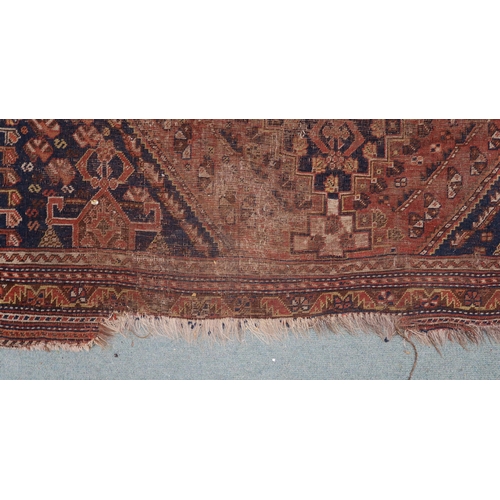 146 - A red ground Persian tribal rug with three geometric medallions, blue spandrels and multiple borders... 