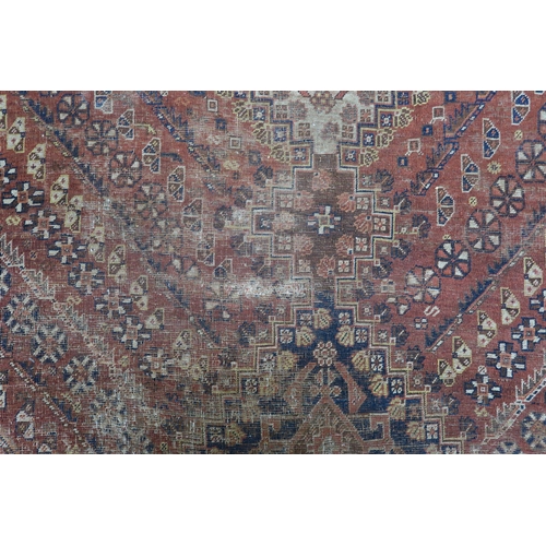 146 - A red ground Persian tribal rug with three geometric medallions, blue spandrels and multiple borders... 