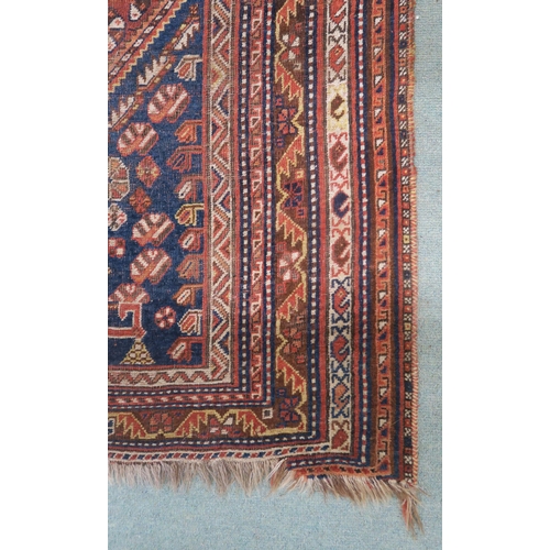 146 - A red ground Persian tribal rug with three geometric medallions, blue spandrels and multiple borders... 