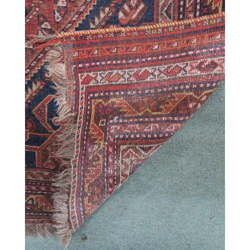 146 - A red ground Persian tribal rug with three geometric medallions, blue spandrels and multiple borders... 