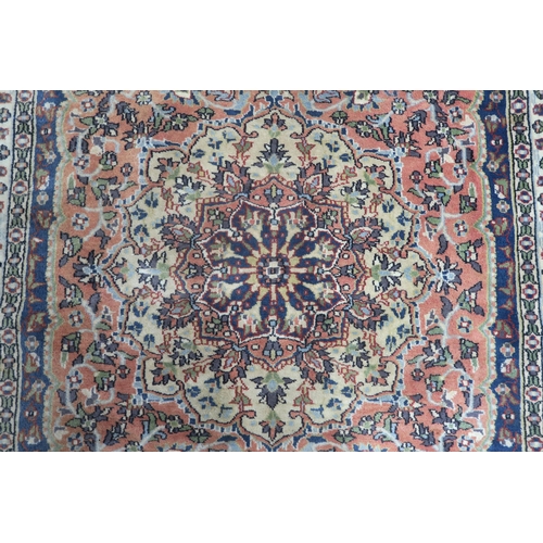 34 - A modern pink ground eastern style rug with floral central medallion and dark blue spandrels, 191cm ... 