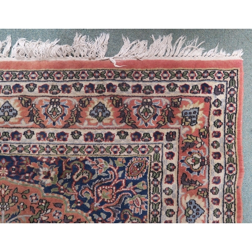 34 - A modern pink ground eastern style rug with floral central medallion and dark blue spandrels, 191cm ... 