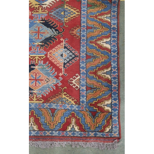 63 - A red ground Kazak rug with all over design and multicoloured borders, 210cm long x 188cm wide