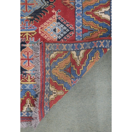 63 - A red ground Kazak rug with all over design and multicoloured borders, 210cm long x 188cm wide