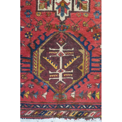 92 - A red ground Heriz runner with geometric medallions and multicoloured border, 381cm long x 88cm wide