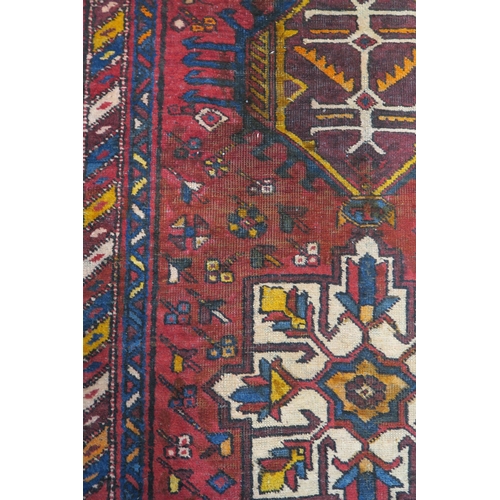 92 - A red ground Heriz runner with geometric medallions and multicoloured border, 381cm long x 88cm wide