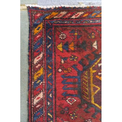 92 - A red ground Heriz runner with geometric medallions and multicoloured border, 381cm long x 88cm wide