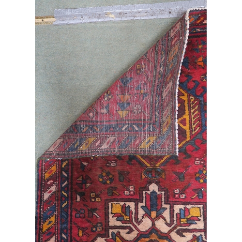 92 - A red ground Heriz runner with geometric medallions and multicoloured border, 381cm long x 88cm wide