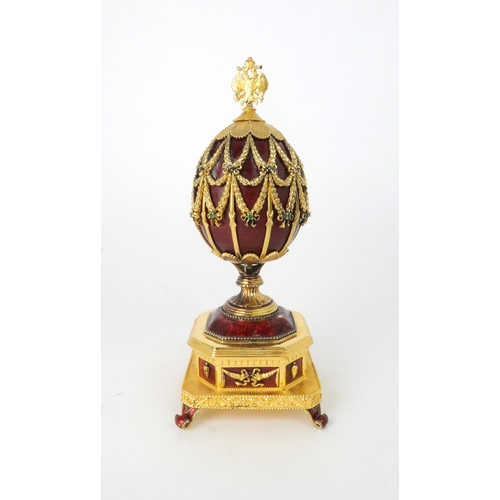 163 - A FRANKLIN MINT MUSICAL GOLD PLATED SILVER FABERGE IMPERIAL EAGLE EGGwith red guilloche enamel and b... 