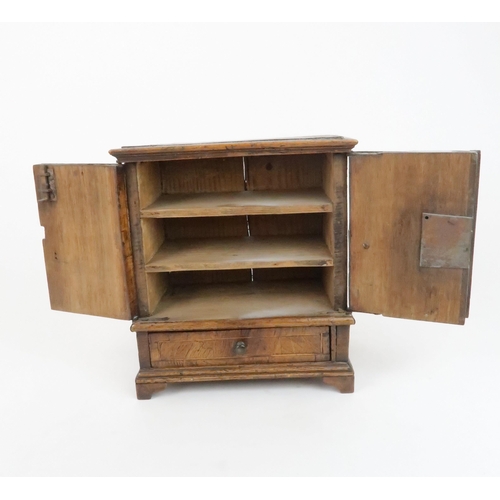 210 - AN APPRENTICE PIECE CHESTthe two door opening to reveal shelves above a drawer, 26cm high... 