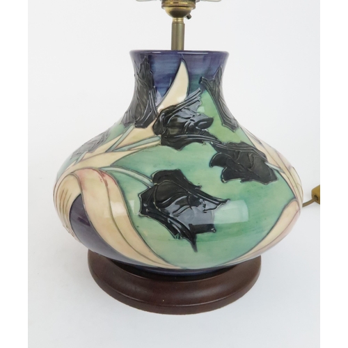 302 - A MOORCROFT BLACK TULIP PATTERN TABLE LAMPdesigned by Sally Tuffin, 29cm high, a matching coaster/tr... 