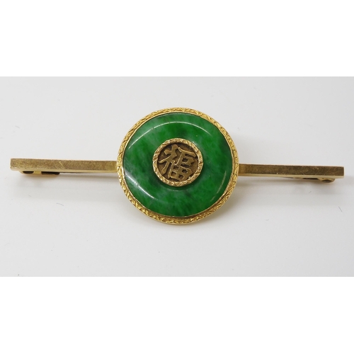 778 - A CHINESE GREEN HARDSTONE RONDEL BROOCHwith Chinese symbols mounted to the middle, the bar brooch is... 