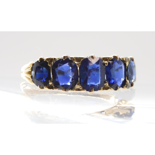 805 - A FIVE SAPPHIRE RINGin a classic yellow metal scrolled mount. Largest sapphire measures approx 5.99m... 