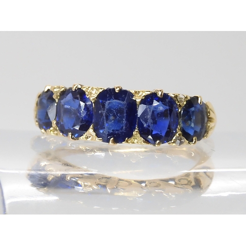 805 - A FIVE SAPPHIRE RINGin a classic yellow metal scrolled mount. Largest sapphire measures approx 5.99m... 