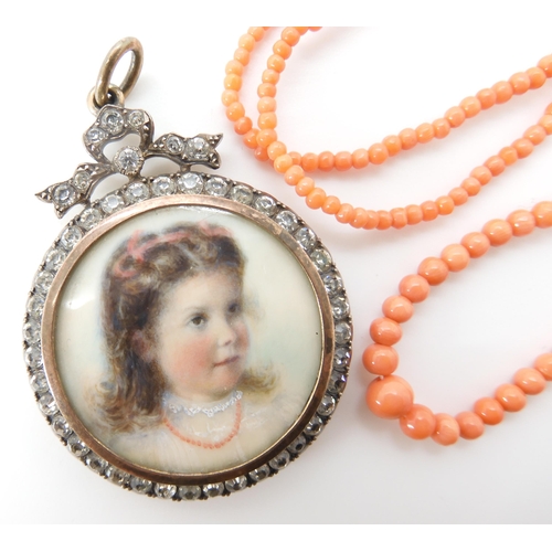 811 - A FRENCH SILVER PORTRAIT LOCKETof a little girl in a coral necklace, in a gilded diamante set frame,... 
