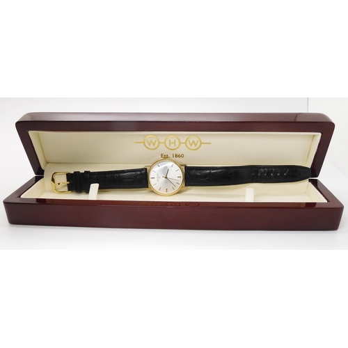 909 - A 9CT GOLD WHW QUARTZ WRISTWATCHwith brushed silvered dial, gold baton numerals and a date aperture.... 